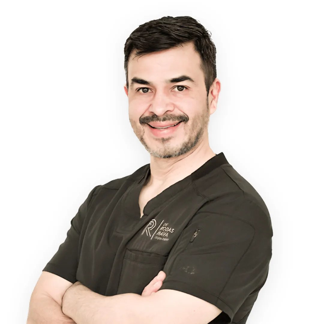 Mommy Makeover in Tijuana, Mexico — Restore Your Confidence 16 Professional portrait of Dr. Rodas Naya, a plastic surgeon, smiling with his arms crossed and wearing gray surgical scrubs.