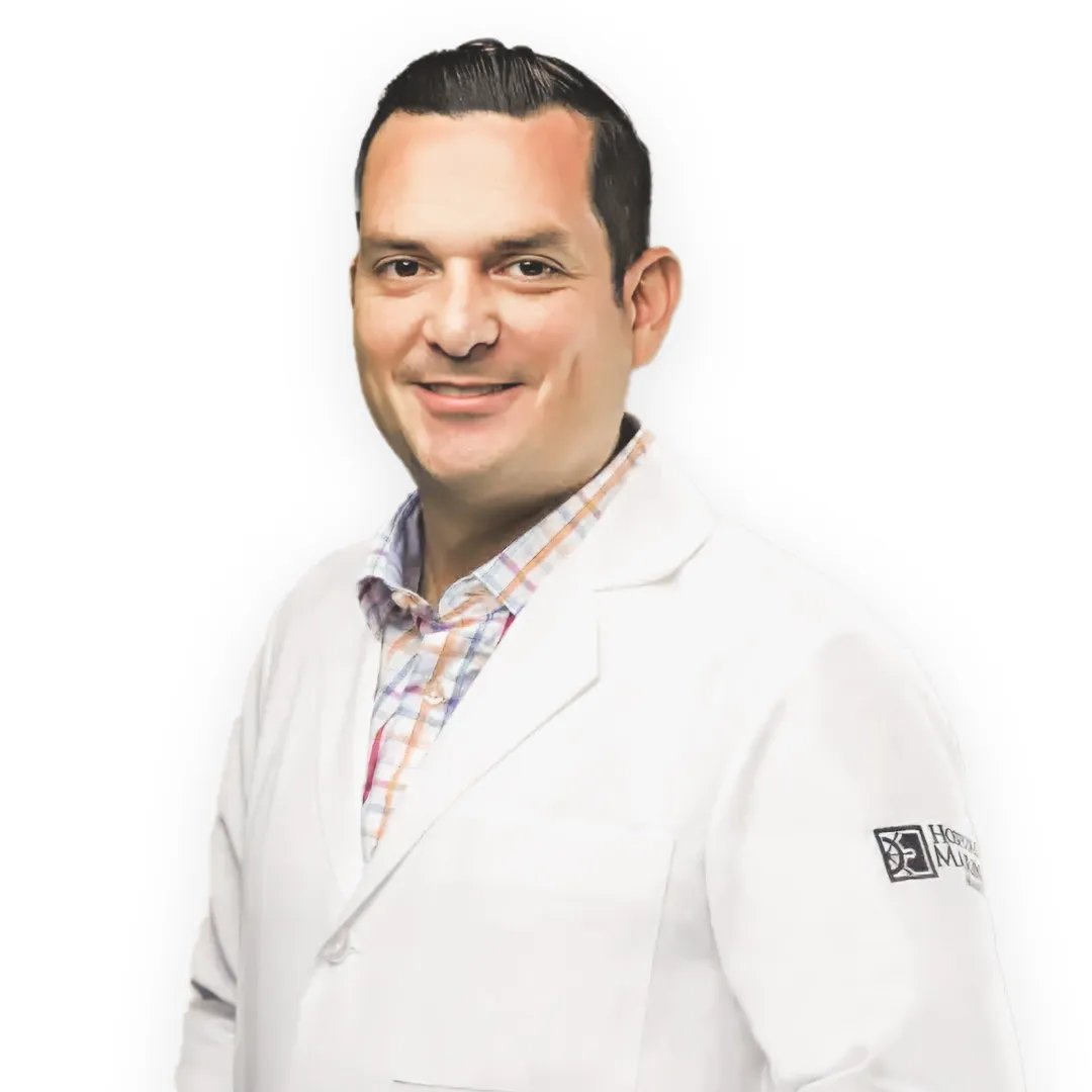 Mommy Makeover in Tijuana, Mexico — Restore Your Confidence 18 Professional portrait of Dr. Javier, a surgeon, smiling and wearing a white lab coat.