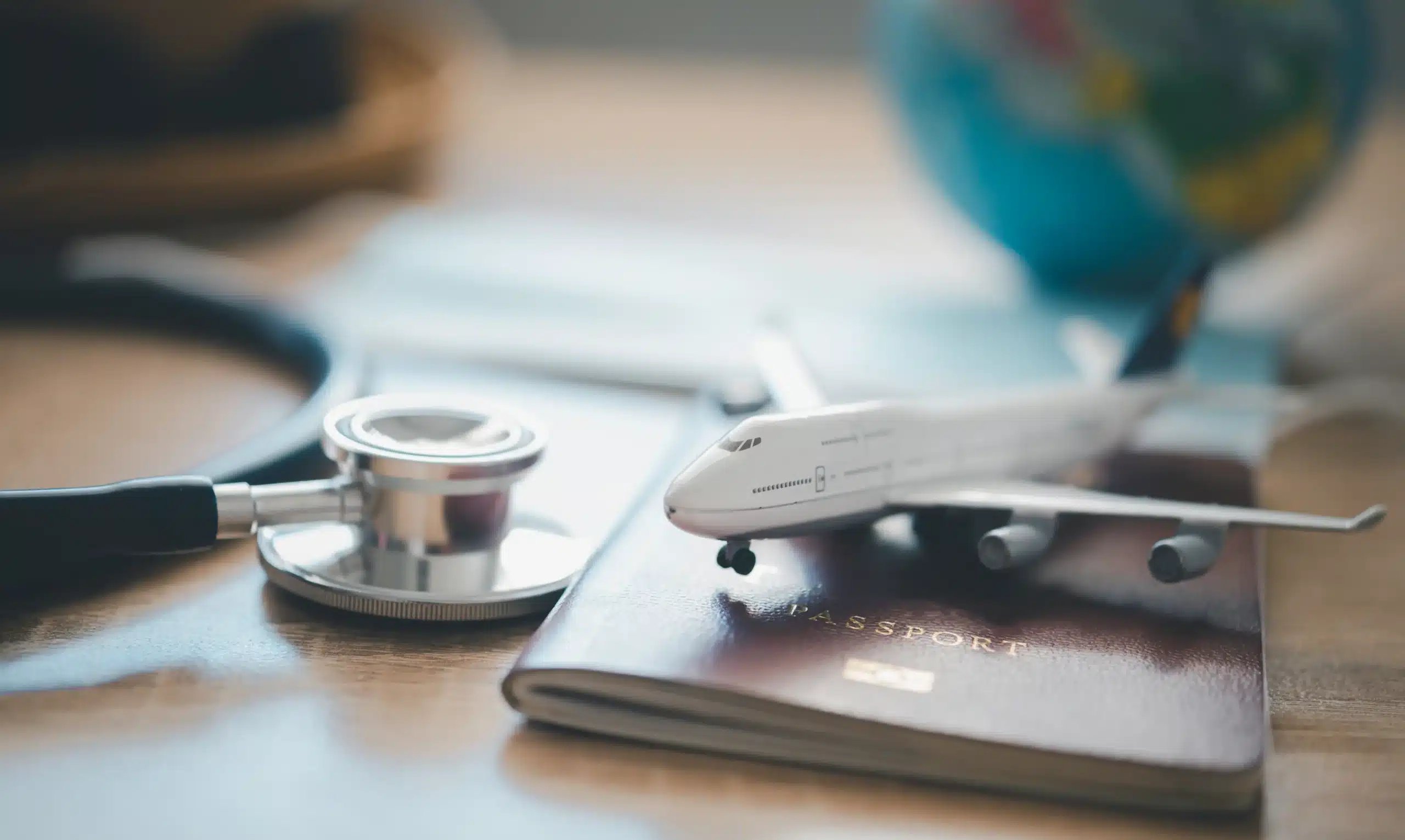 Stethoscope, toy airplane, and passport on a desk, representing the planning of medical tourism in Mexico and safety for international patients.
