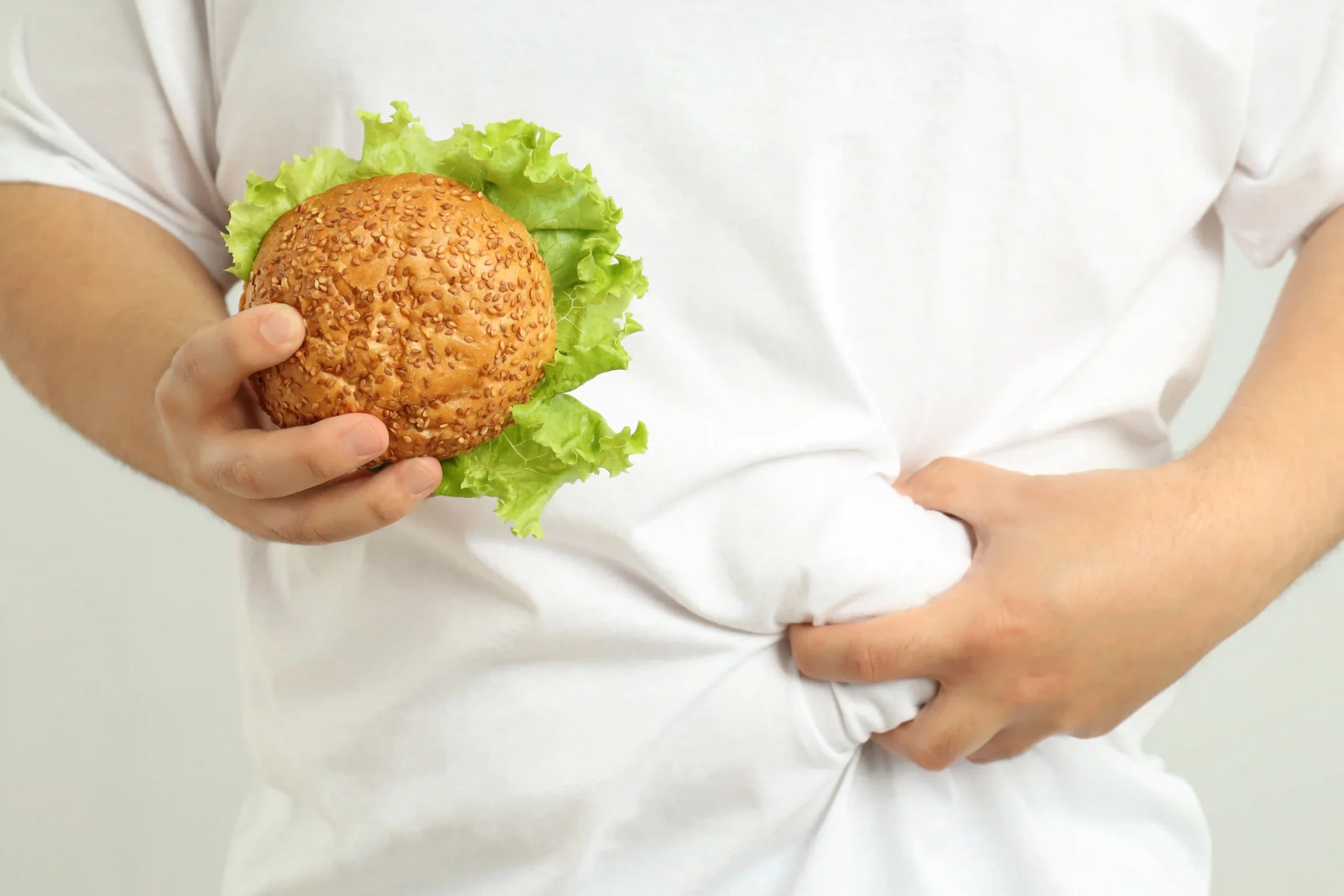 Gastric Balloon in Tijuana, Mexico 19 Man with burger pinching fat, exploring gastric balloon in Tijuana options.