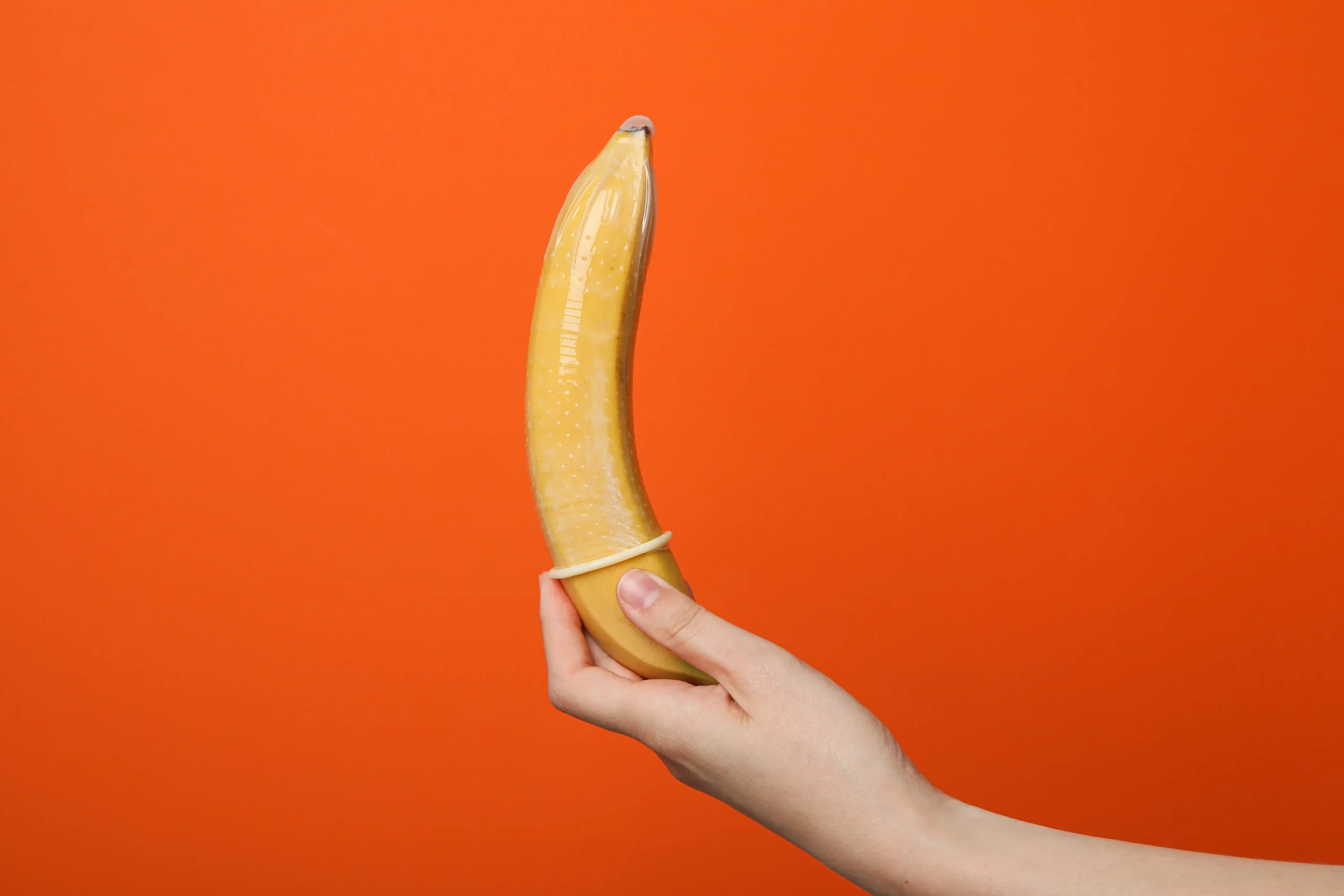 Penis Enlargement in Tijuana, Mexico 13 Symbolic image of a hand placing a condom on a banana, representing safe surgery options to make penis bigger in Mexico and sexual health wellness.