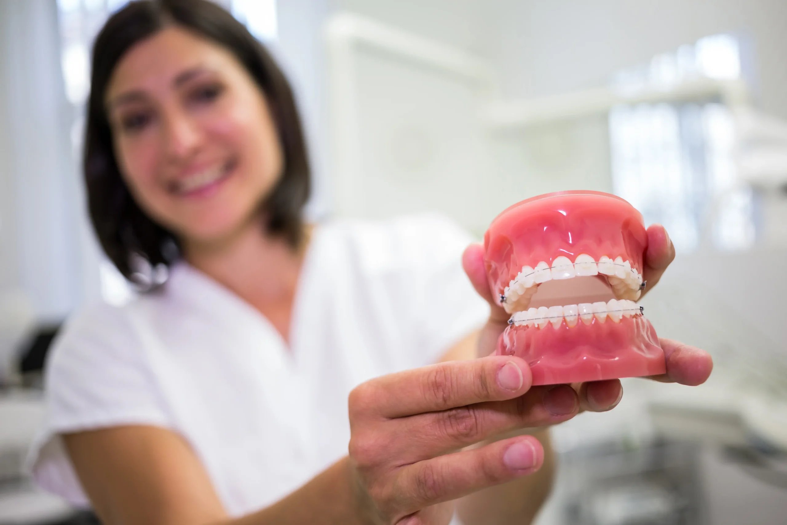Dentures in Tijuana, Mexico 11 A smiling board-certified dentist holding a dental model to explain affordable dentures in Tijuana options.
