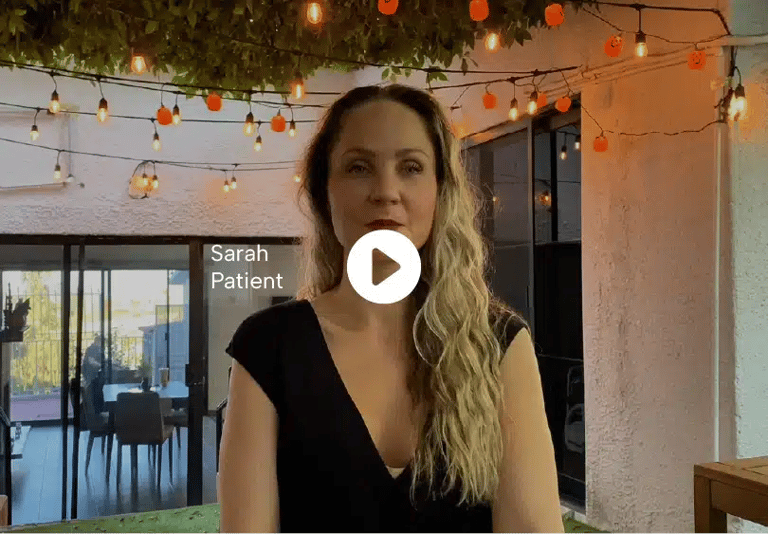 Sarah, a patient, standing outdoors with decorative lights in the background, giving her testimonial about her medical experience.