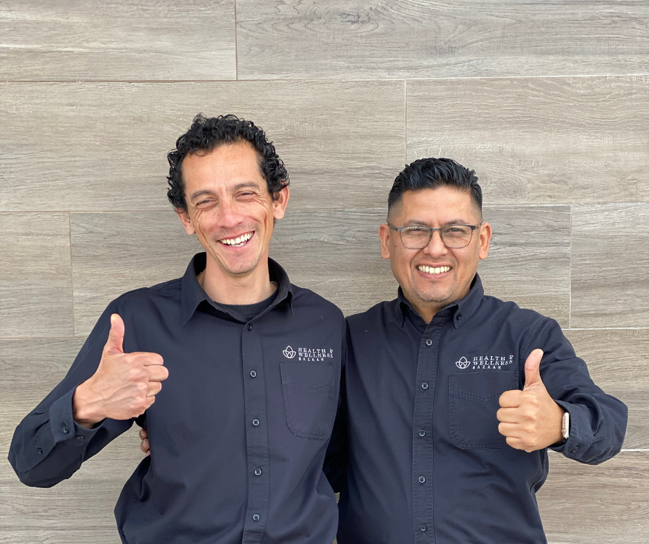 A photo of two smiling patient coordinators, Abraham and Jaime, giving a thumbs-up at Health & Wellness Bazaar in Tijuana.