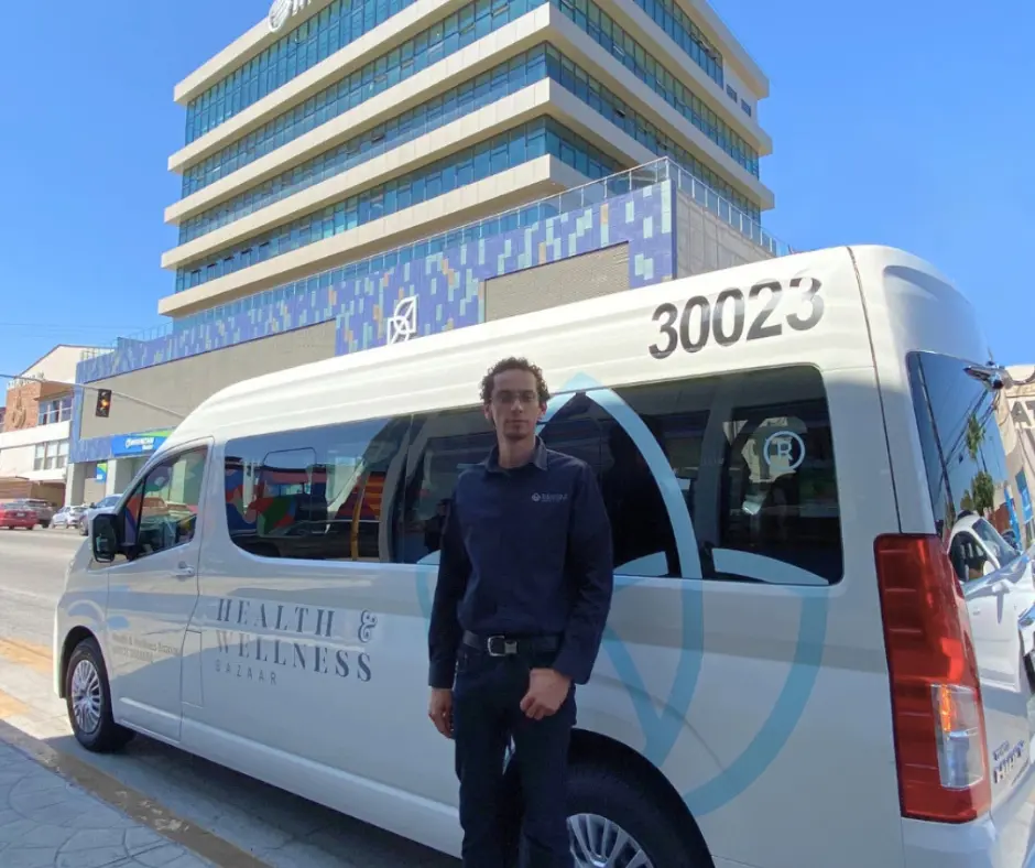 How to Find a Safe Plastic Surgery Center in Mexico – 10-Step Safety Checklist 3 A professional photo of Abraham, a patient coordinator, standing proudly next to a Health & Wellness Bazaar transport van in Tijuana.