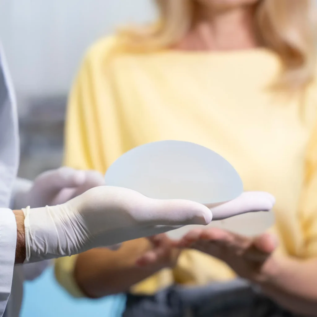 Breast Augmentation In Tijuana, Mexico 16 Plastic surgeon with sterile gloves presenting a high-quality silicone breast implant to a patient during a consultation for breast augmentation in Tijuana.