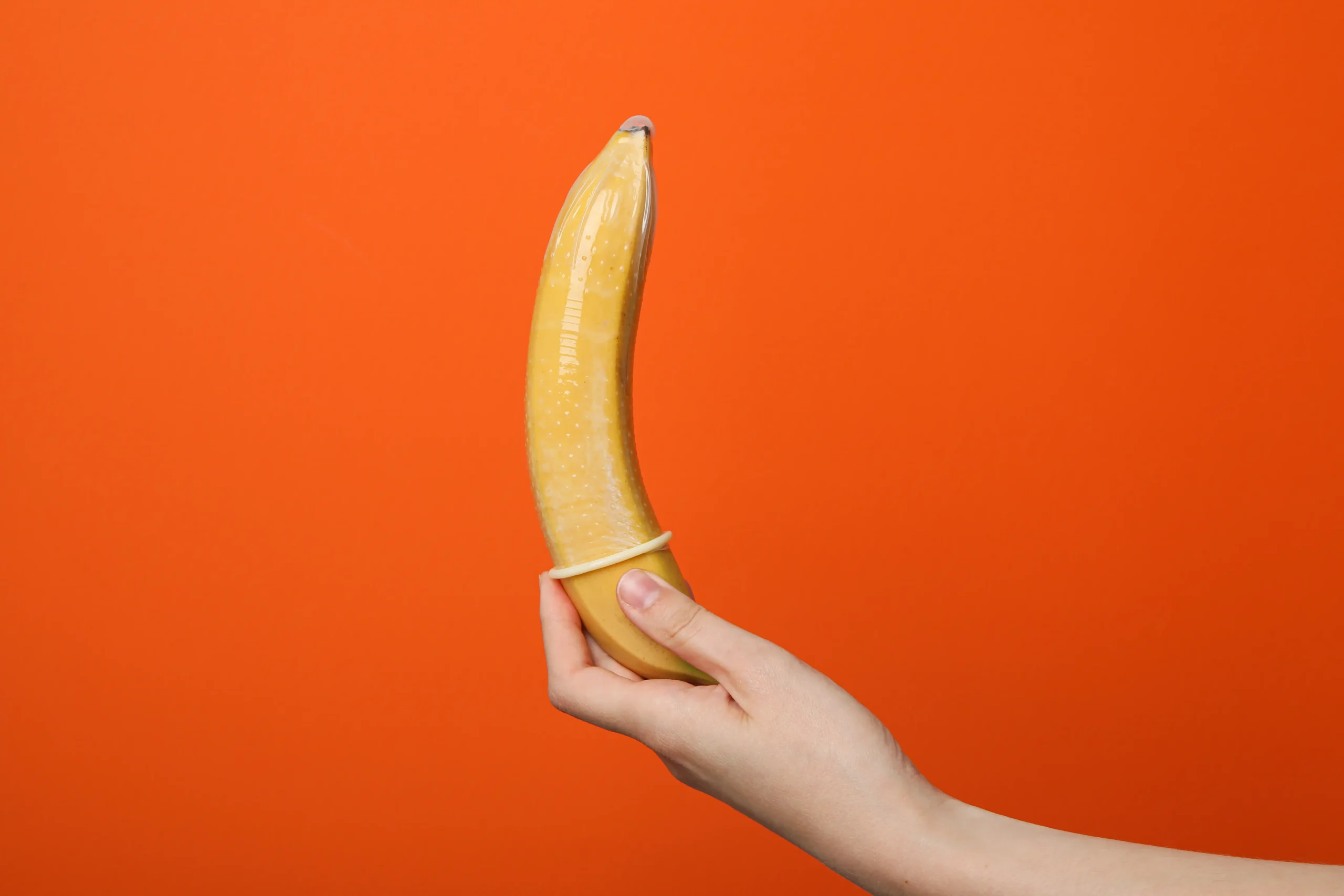 Penis Enlargement in Tijuana, Mexico 13 Symbolic image of a hand placing a condom on a banana, representing safe surgery options to make penis bigger in Mexico and sexual health wellness.