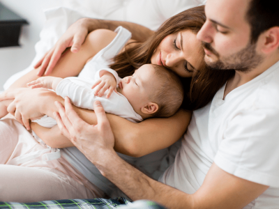 Fertility Success – Happy Family After Treatment at HWBazaar Loving parents cuddling their newborn baby, symbolizing fertility success and parenthood.
